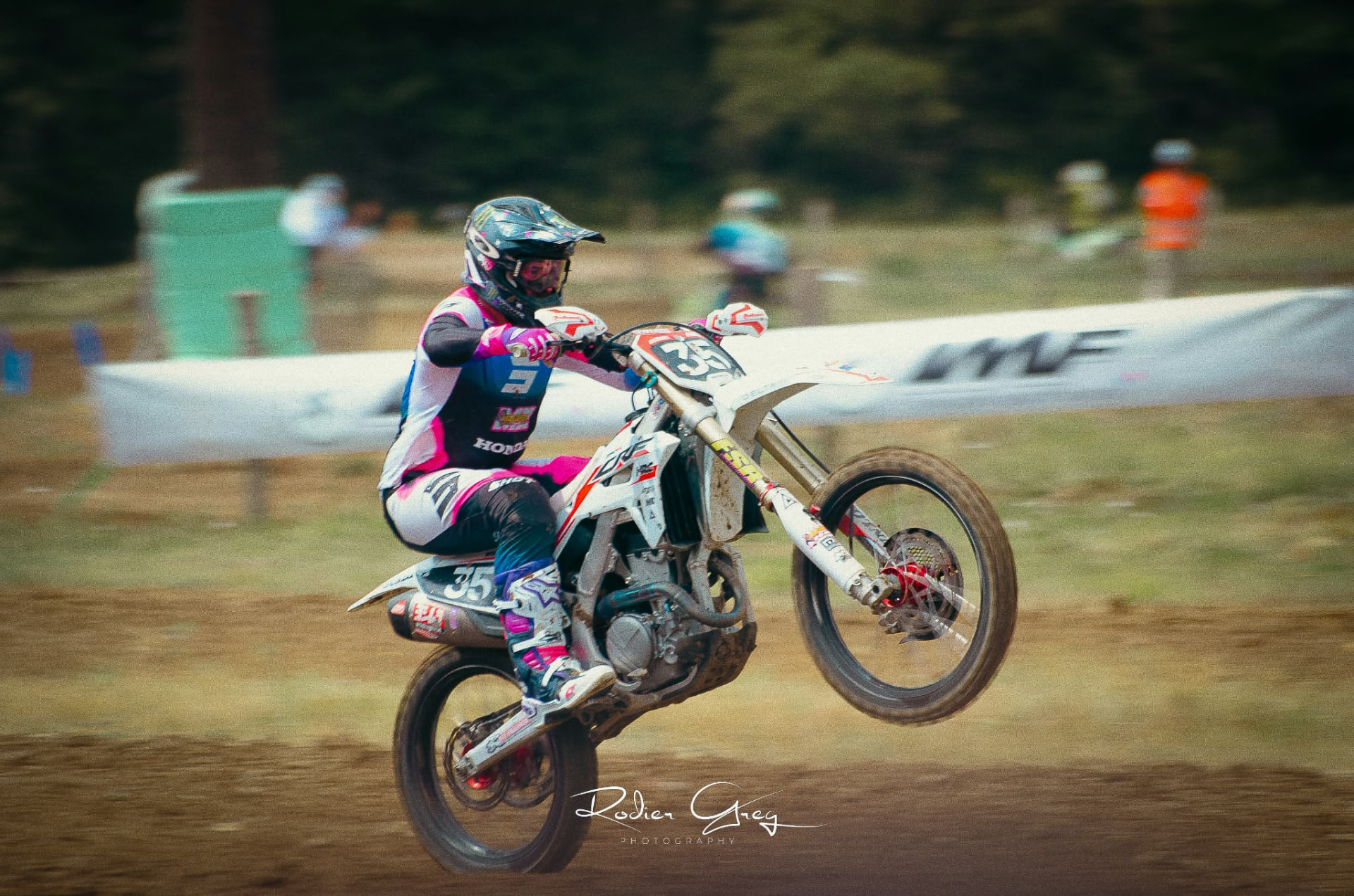 Pilote de motocross en wheeling sur la piste