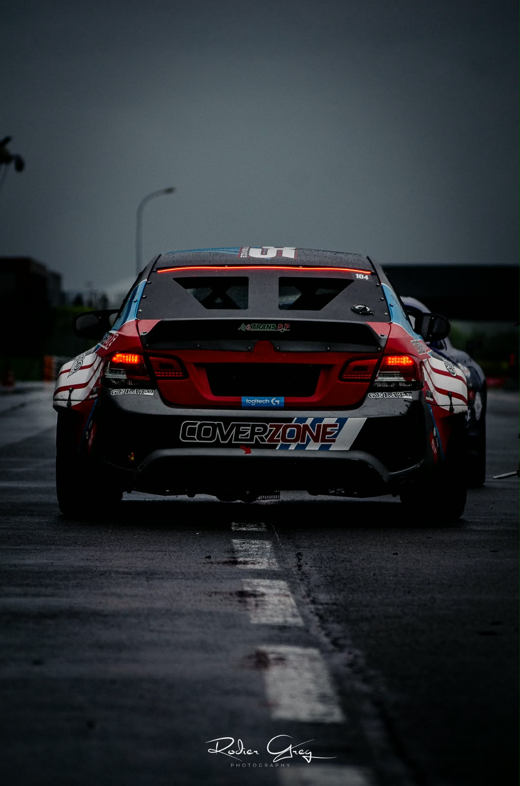 Voiture de course à l'arrêt sur piste humide au crépuscule